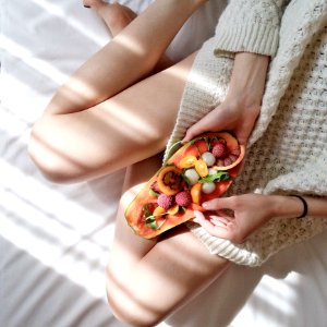 Person Holding Papaya Fruit On Bed