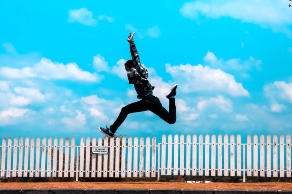 Man Jumping Over White Fence