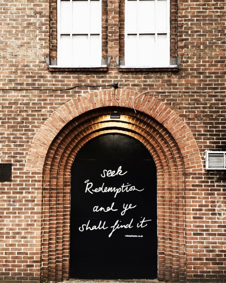Black Wooden Door With Quote Printed At Daytime