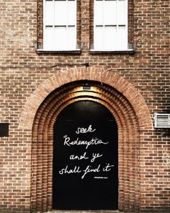 Black Wooden Door With Quote Printed At Daytime