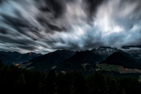 Time Lapse Photography Of Pine Trees Near Mountains Under Grey Clouds