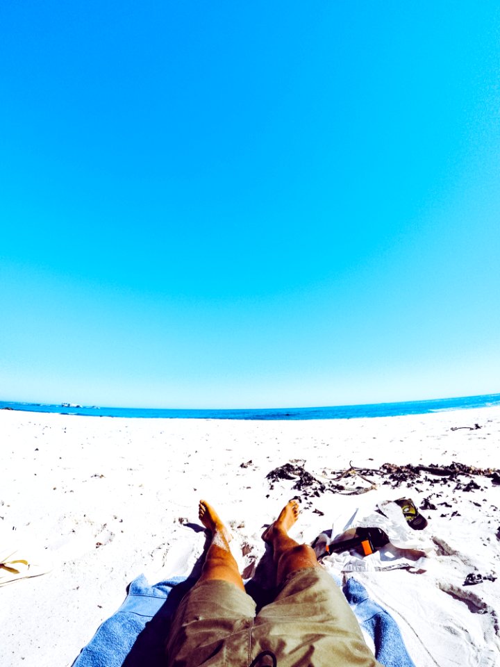 Man In Gray Shorts Laying On White Sand In Beach