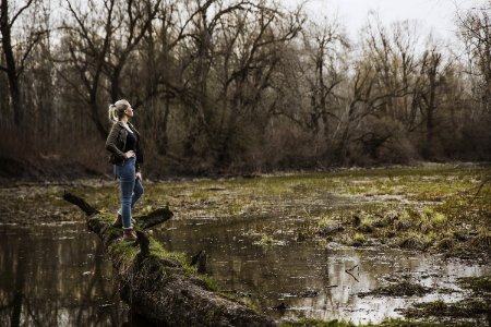 Woman Standing On Driftwood Above Body Of Water photo