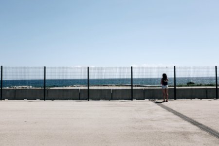 Woman Standing Near Fence And Body Of Water photo