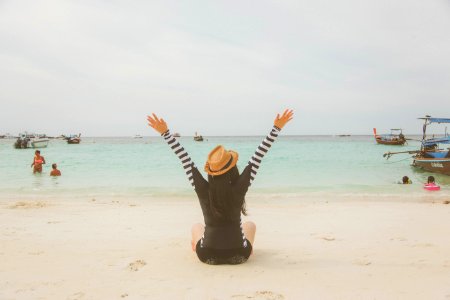 Woman Sitting At The Beach Near Boats And People During Day photo