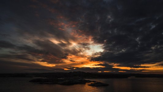 Silhouette Of Island Under Grey Clouds During Golden Hour photo