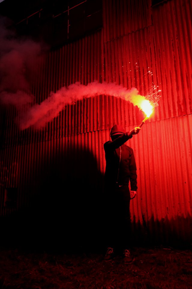 Person Wearing Zip-up Hooded Jacket While Holding Flare