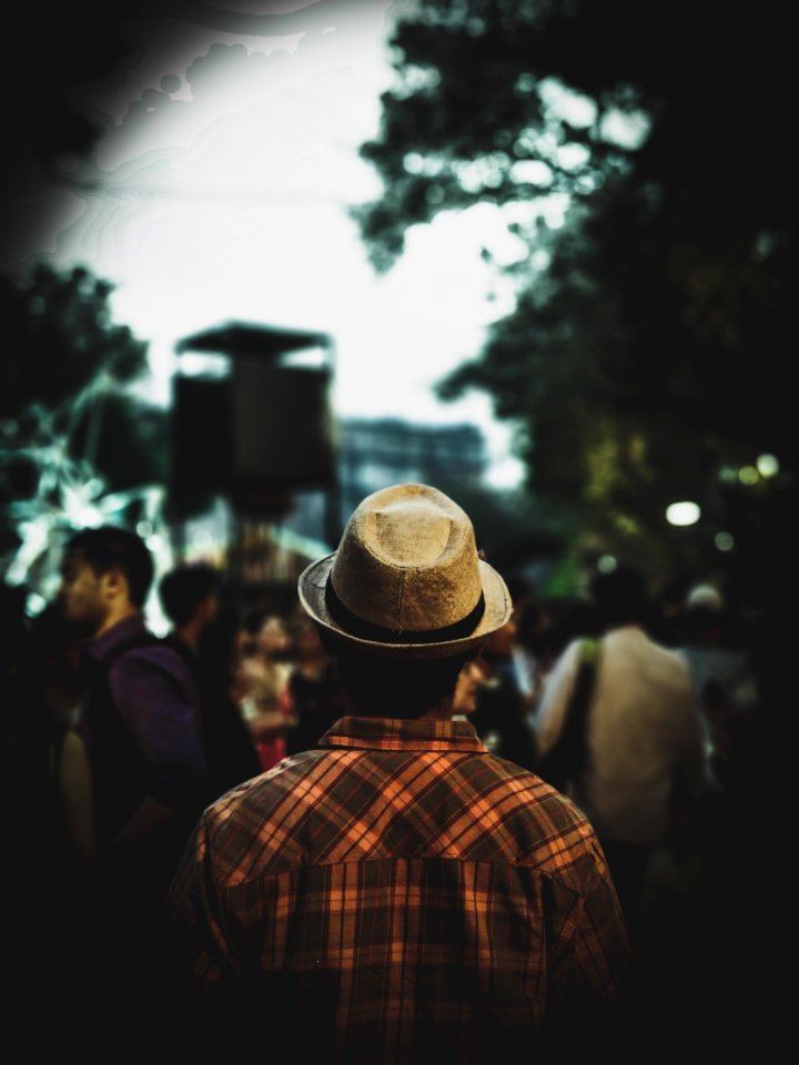 Man Wearing Fedora Hat And Plaid Shirt Facing People