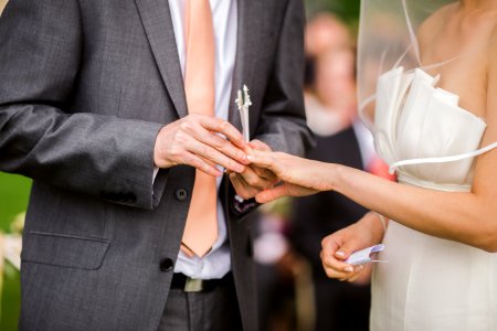 Photo Of Groom Putting Wedding Ring On His Bride photo