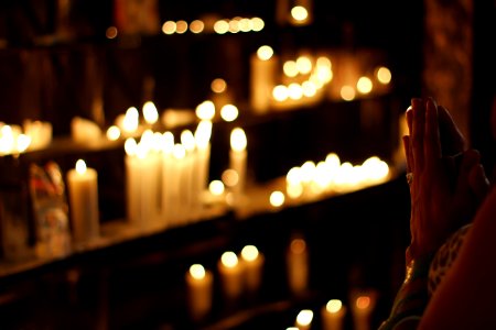 Close Up Photograph Of Person Praying In Front Lined Candles photo
