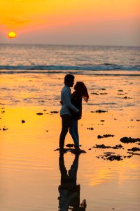 Man And Woman Hugging By The Seashore During Sunset photo