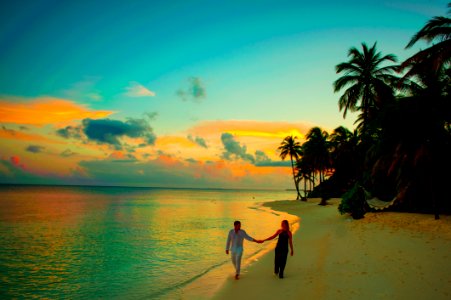 Man And Woman Holding Hand Walking Beside Body Of Water During Sunset photo