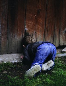 Photo Of Boy Peeking On Brown Wooden Fence photo
