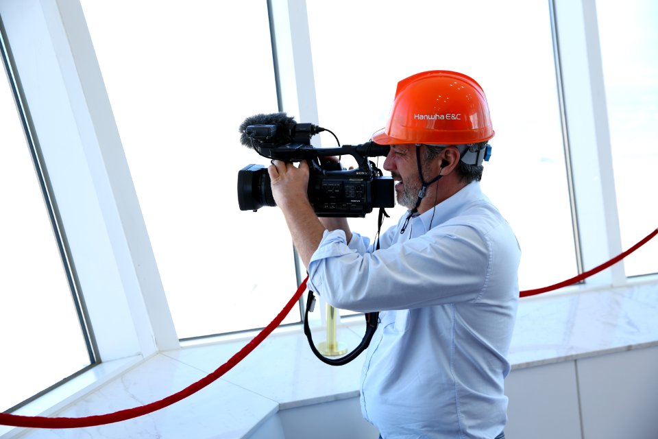 Person In Blue Dress Shirt Holding Black Professional Vidreo Camera