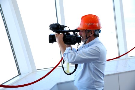 Person In Blue Dress Shirt Holding Black Professional Vidreo Camera