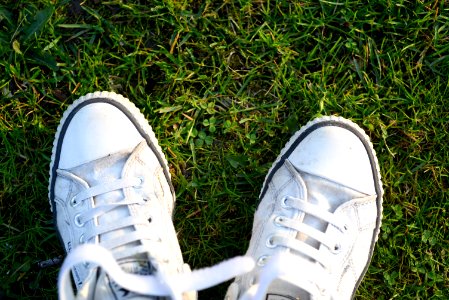 Pair Of White Lace-up Sneakers On Top Green Grass