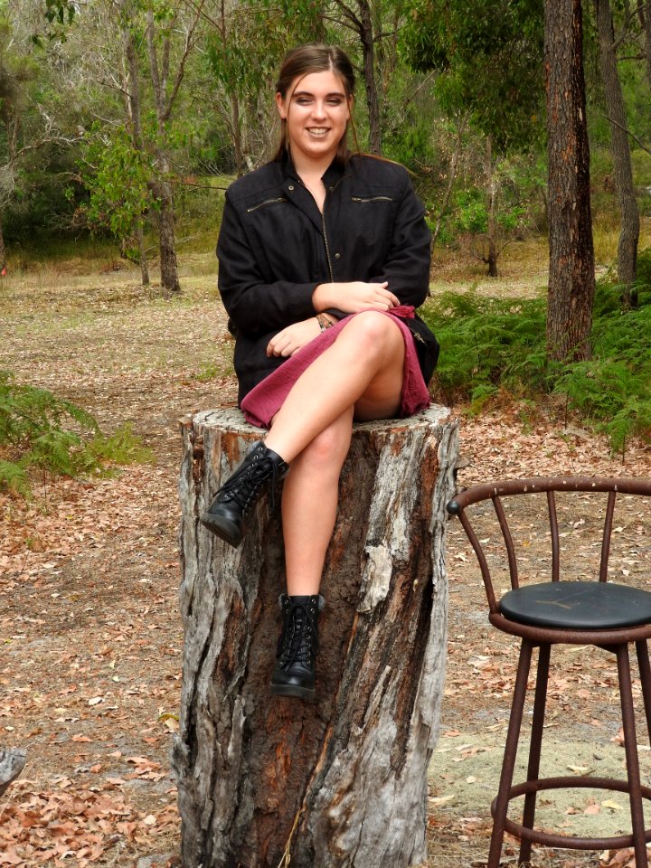 Woman Wearing Black Jacket Sitting On Tree Log Near Bar Stool