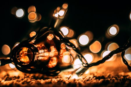 Low-light Photo Of Amber Glass Bottle With String Lights And Beige Bokeh
