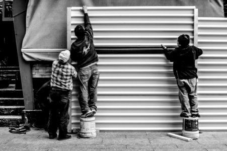 Grayscale Photo Of Three Men Arranging Metal Wall