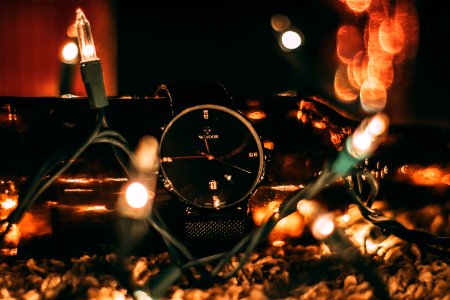 Round Silver-colored Analog Watch With Black Band Surrounded With String Lights Selective Focus Photography photo