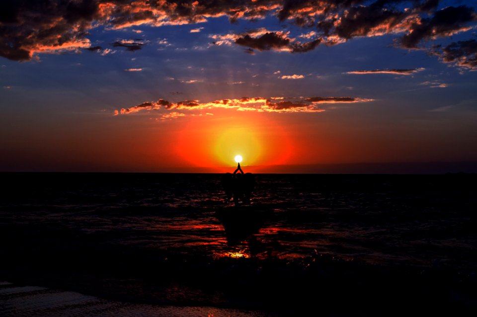 Silhouette Photography Of Three People Pointing The Sun photo