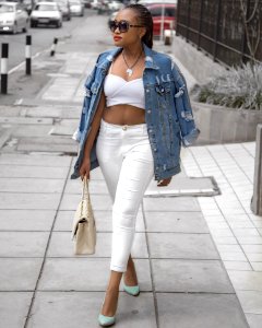 Photo Of Woman Wearing White Crop Top And Denim Jacket Walking In Pavement Holding Bag photo