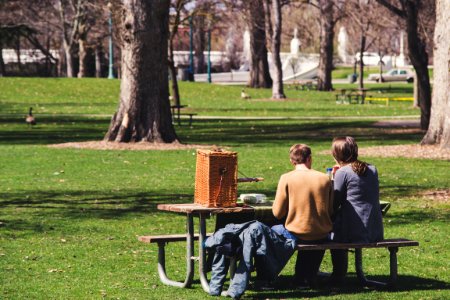 Man And Woman Sitting On Brown Wooden Picnic Table photo