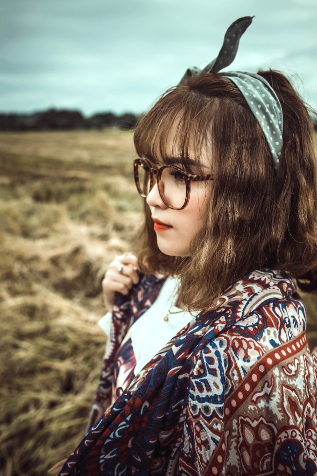 Selective Focus Shot Of Woman In White And Brown Floral Standing On Grass Field