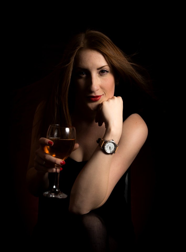Woman Wearing Black Dress Holding Clear Wine Glass In Dark Room