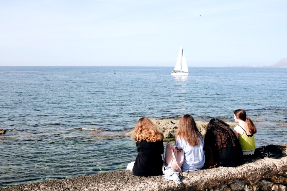 Four Women Sitting Near Sea At Daytime photo