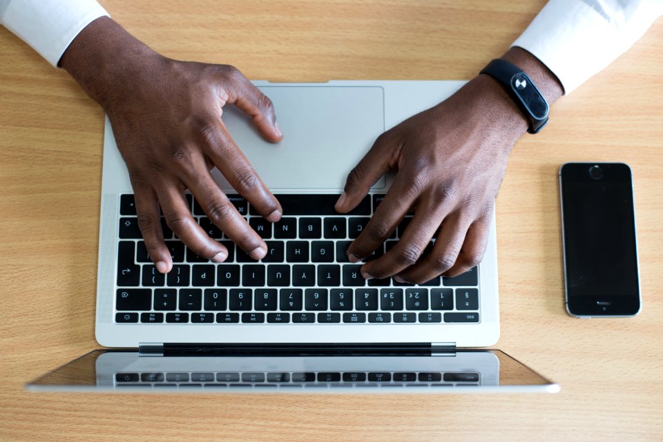 Closeup Photo Of Persons Hands On Macbook Beside Space Gray Iphone 5s