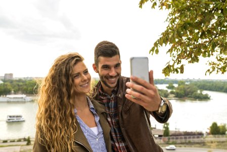 Man Holding Smartphone Beside Woman Near Tree photo