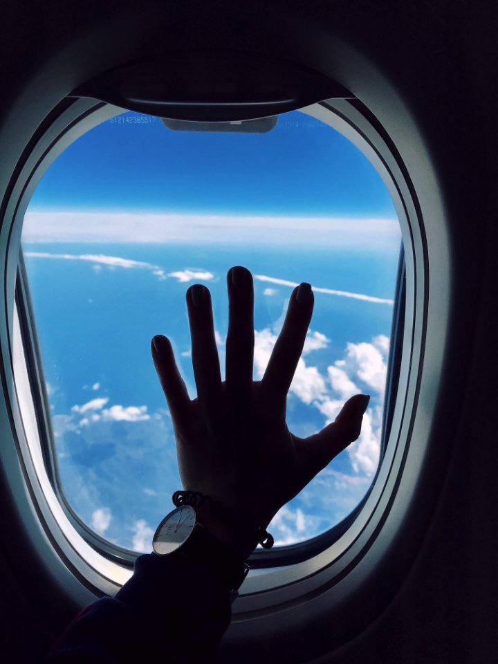 Photography Of Persons Left Hand Touching An Airplanes Window