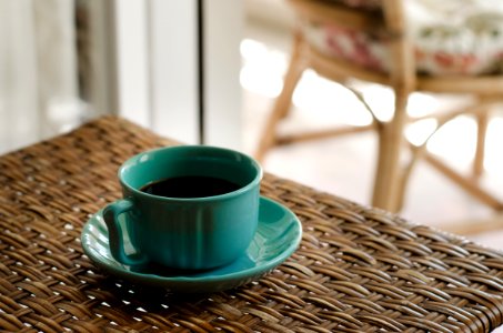 Blue Coffee Cup With Saucer Filled With Coffee On Top Of Wicker Table photo