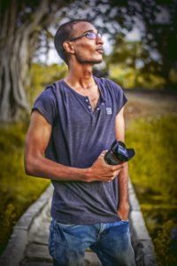 Shallow Focus Photography Of Man Wearing Gray T-shirt Holding Dslr Camera Lens photo
