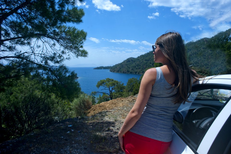 Woman In Gray Tank Top Beside White Car Near Body Of Water photo