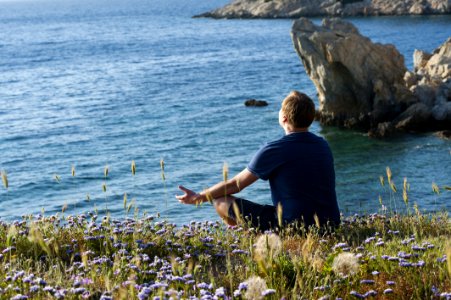 Man Sitting On Flower Fields Facing Ocean photo