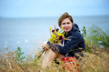 Woman Sitting On Grass Holding Flowers Wearing Black Hoodie photo