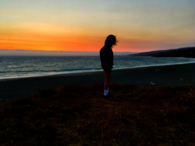 Person Standing On Seashore During Sunset photo