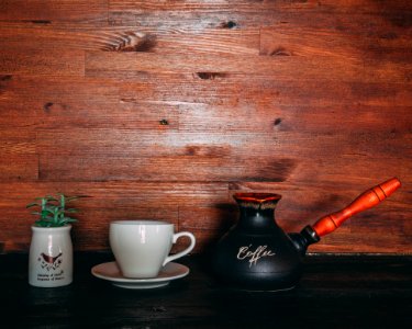 Black And Orange Turkish Coffee Pot On Table Near Cup And Saucer photo