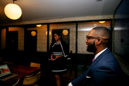 Man In Blue Formal Suit Jacket Sitting Near Standing Woman photo