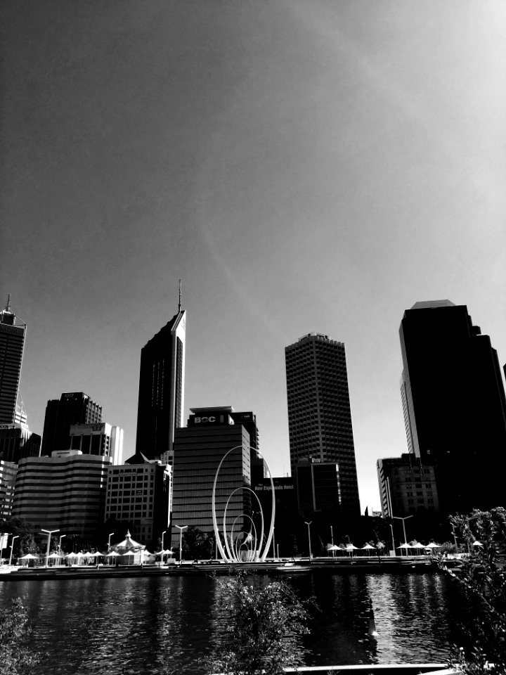 Grayscale High-rise Building Mirrored On Calm Body Of Water photo