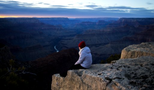 Person Wearing White Hoodie Sitting On Cliff At Daytime photo