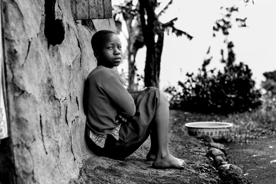 Greyscale Photography Of Boy Sitting Behind Wall