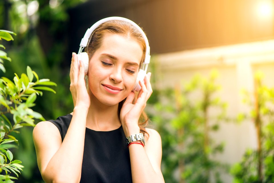 Woman Wearing Black Sleeveless Dress Holding White Headphone At Daytime photo