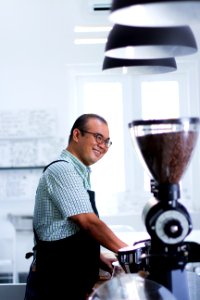 Man Wearing Plaid T-shirt And Black Apron In Front Of Coffeemaker photo