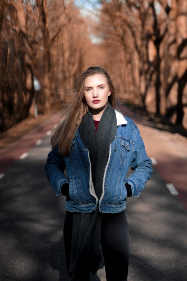 Woman Standing On Asphalt Road Surrounded By Bare Tree