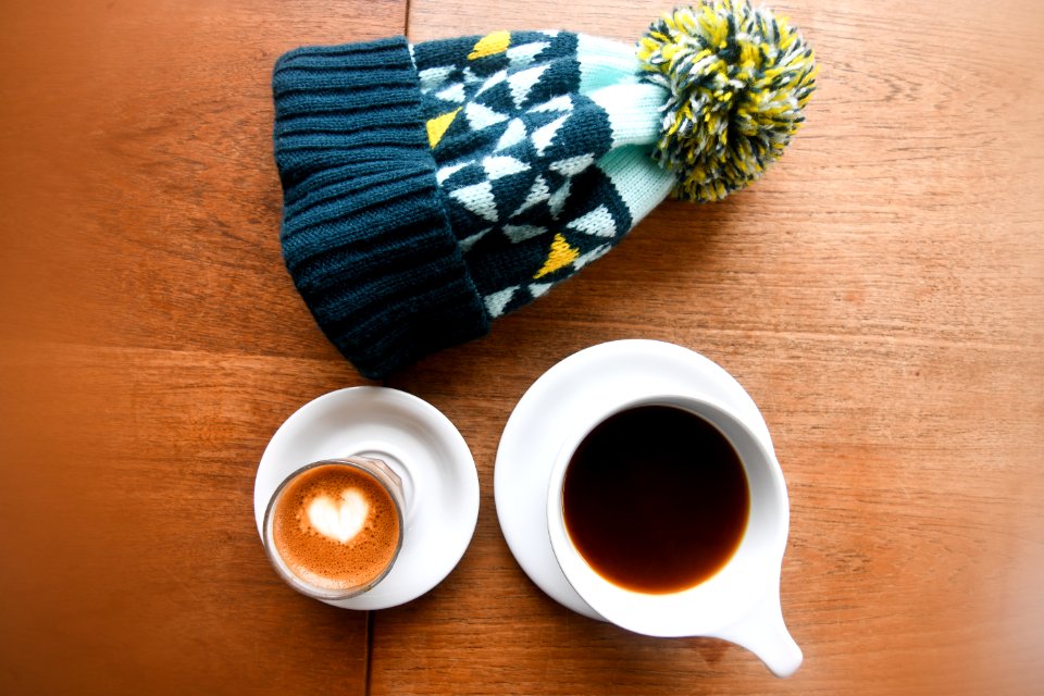 High Angle Photo Of Mug Filled With Coffee Beside Bobble Hat