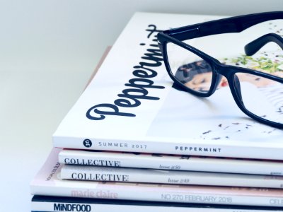 Photo Of Eyeglasses On Top Of Magazines photo