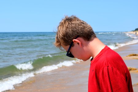 Photo Of Boy Wearing Red Shirt And Sunglasses On Seashore photo